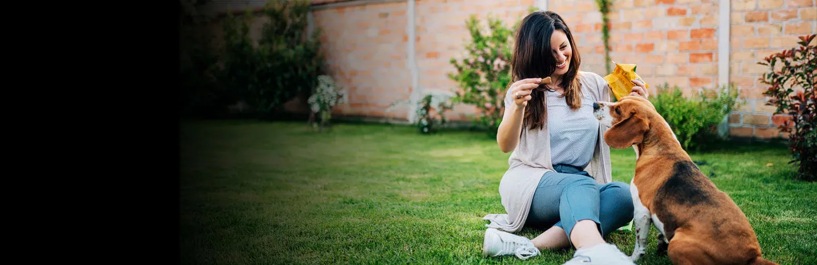 Woman giving dog treat in tick free back yard